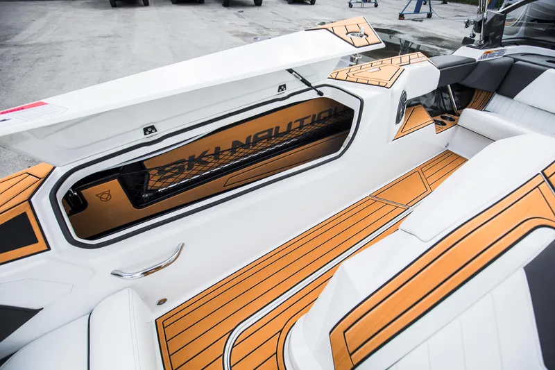 Slide: The Image of 2025 Nautique Ski boat interior with open storage compartment and stylish orange accents. - 14