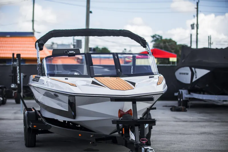Slide: The Image of 2025 Nautique Ski boat on trailer, parked outdoors, showcasing sleek design and modern features. - 4