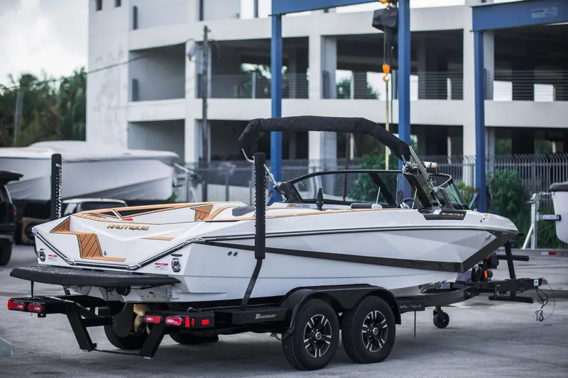 Slide: The Image of 2025 Nautique Ski boat on trailer, parked outdoors near modern building. - 5