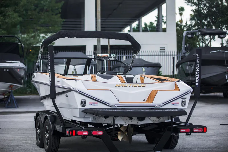 Slide: The Image of 2025 Nautique Ski boat on trailer, rear view, in a marina setting. - 6