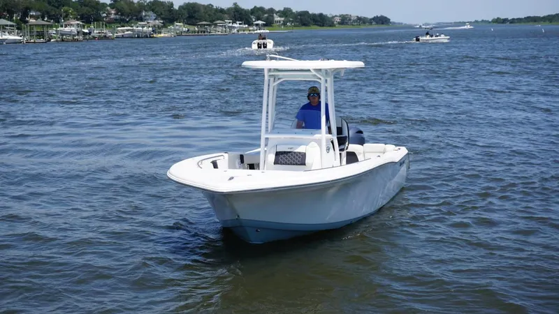 Slide: The Image of 2021 Tidewater 220 LXF boat cruising on a sunny day in open water. - 2