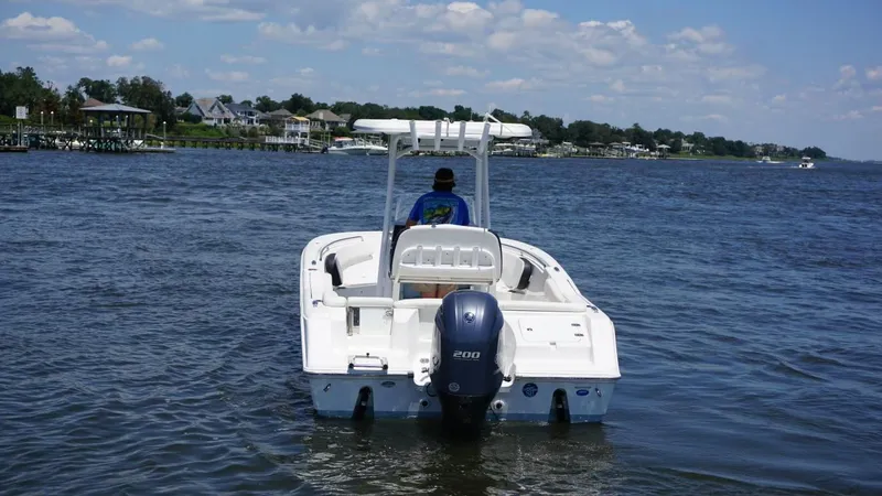 Slide: The Image of 2021 Tidewater 220 LXF boat on a calm lake with scenic shoreline. - 4