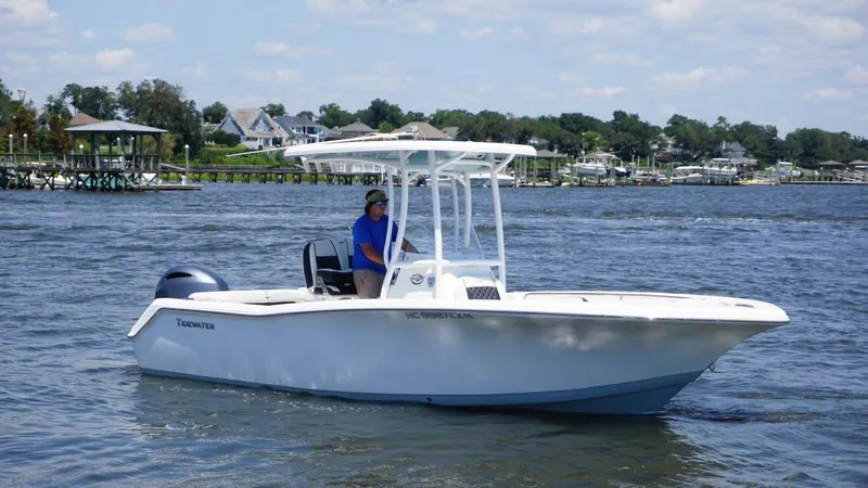 Slide: The Image of 2021 Tidewater 220 LXF boat cruising on a scenic lake with a person onboard. - 6