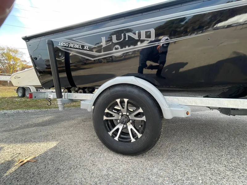 Slide: The Image of 2025 Lund 1650 Rebel XL SS boat on trailer, black exterior, close-up view. - 7
