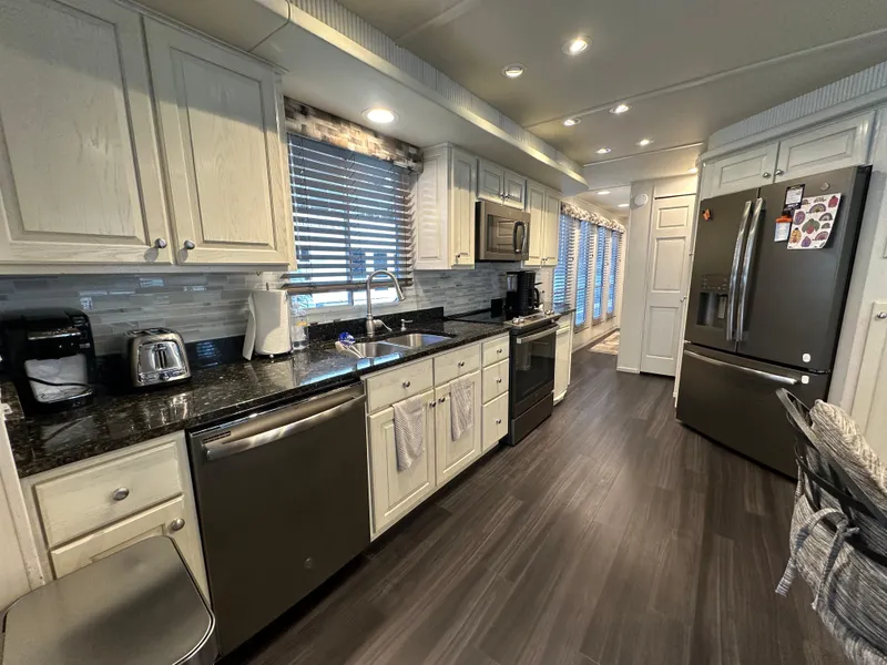 Slide: The Image of Modern kitchen in a 2001 Sharpe 16x80 houseboat with sleek appliances and dark wood flooring. - 18