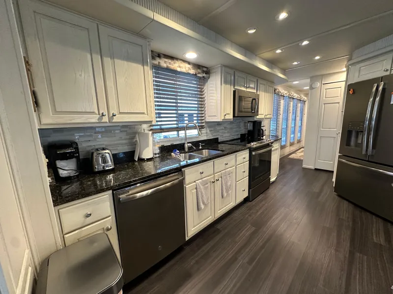 Slide: The Image of Modern kitchen in 2001 Sharpe 16x80 houseboat with stainless appliances and dark wood flooring. - 19