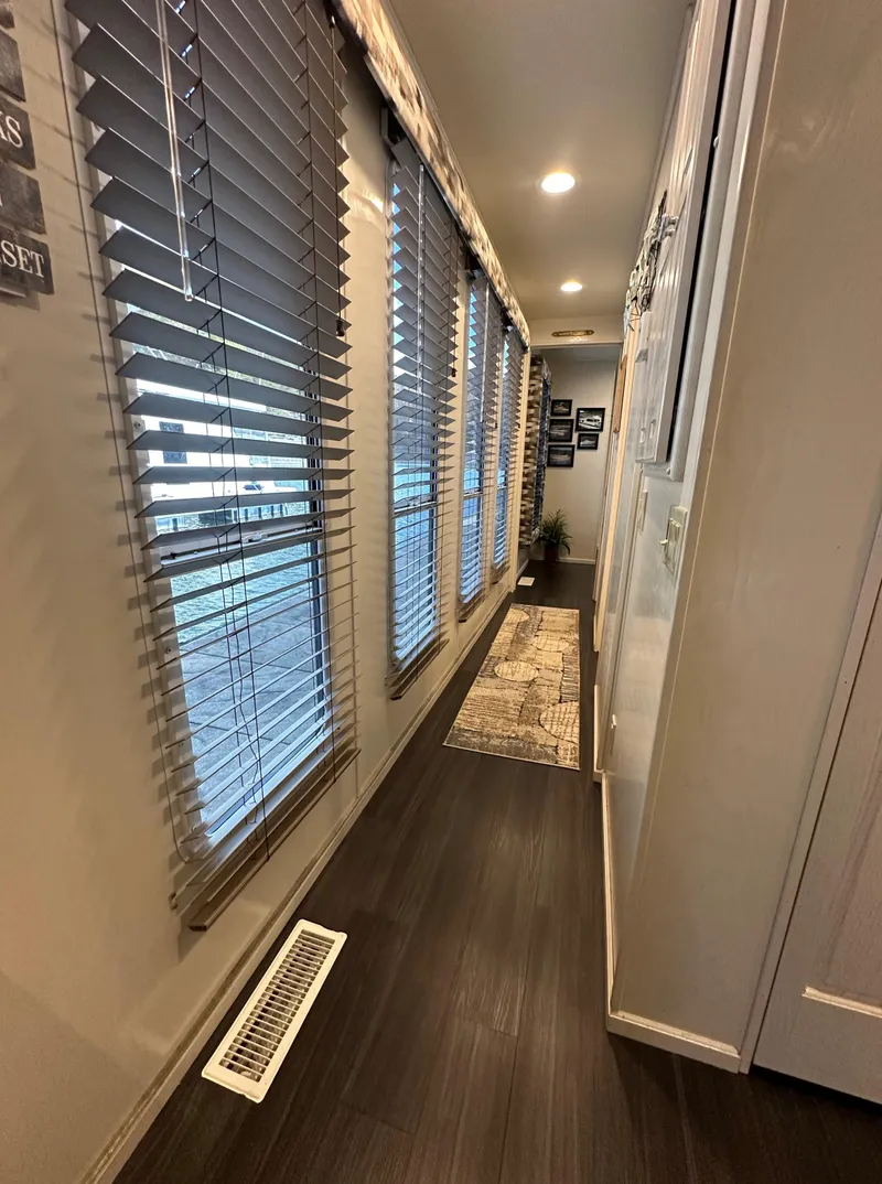 Slide: The Image of Narrow hallway with wooden flooring, large windows, and wall decor in a 2001 Sharpe 16x80 model. - 28