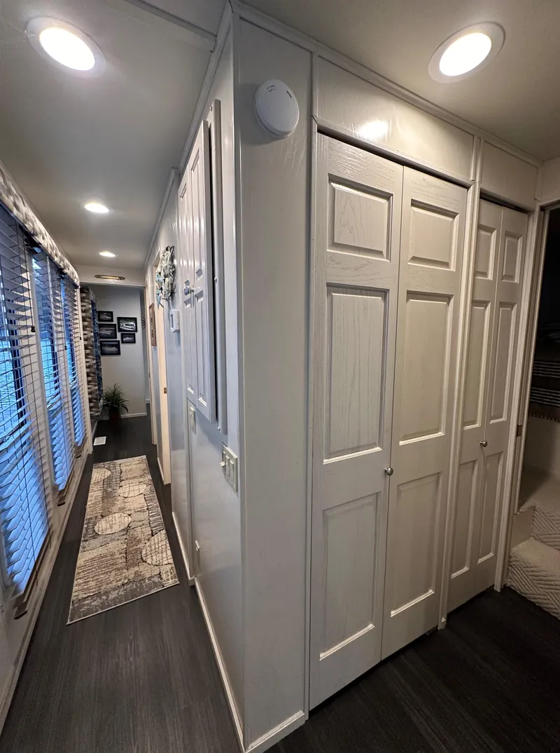 Slide: The Image of Narrow hallway in 2001 Sharpe 16x80 houseboat with white closets and dark flooring. - 29