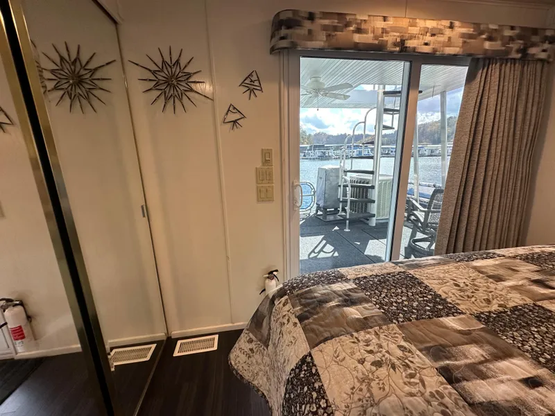 Slide: The Image of Interior of 2001 Sharpe 16x80 houseboat bedroom with quilted bedspread and sliding glass door. - 49
