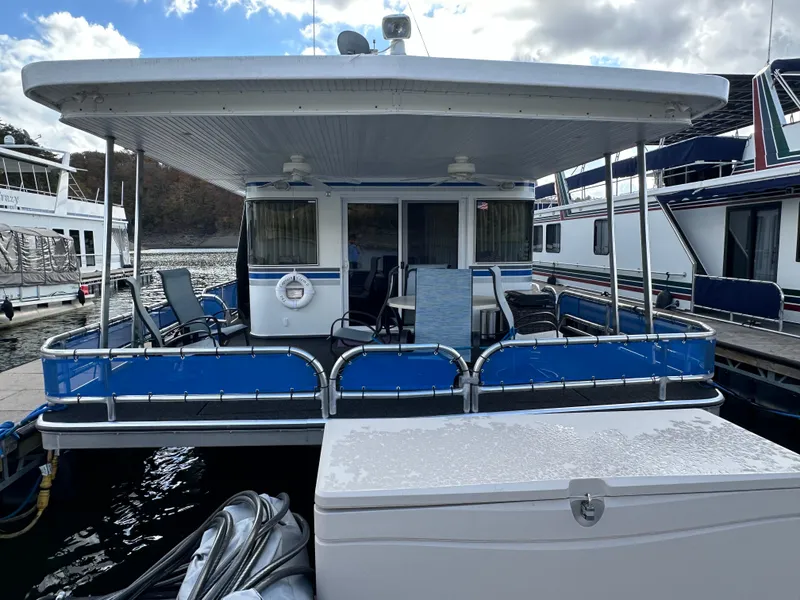 Slide: The Image of 2001 Sharpe 16x80 houseboat docked, featuring blue accents and outdoor seating. - 9