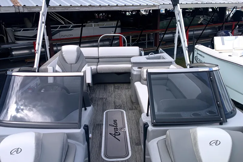 Slide: The Image of 2023 Avalon Catalina Elite Windshield boat interior with seating and windshield, docked in marina. - 6
