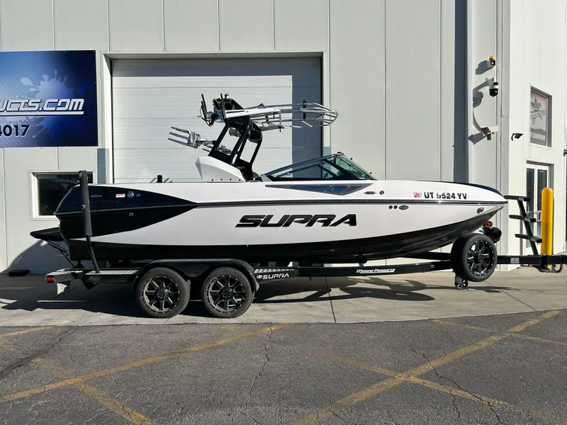 Slide: The Image of 2015 Supra SC400-550 boat on trailer, parked outside a building. - 0