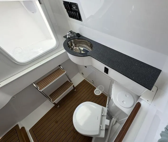 Slide: The Image of 2025 Southport 30 FE boat bathroom with sink, toilet, and wooden flooring. - 21