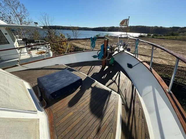 Slide: The Image of 1983 DeFever 41 Trawler deck with wooden flooring, docked by a scenic lake. - 15