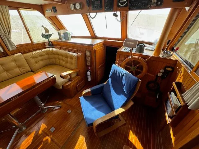 Slide: The Image of Interior of 1983 DeFever 41 Trawler with wooden helm, seating, and nautical decor. - 17