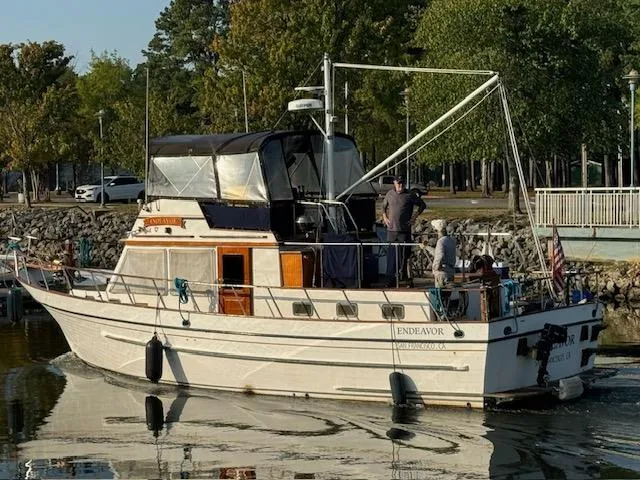 Slide: The Image of 1983 DeFever 41 Trawler boat docked on calm water, surrounded by trees. - 2