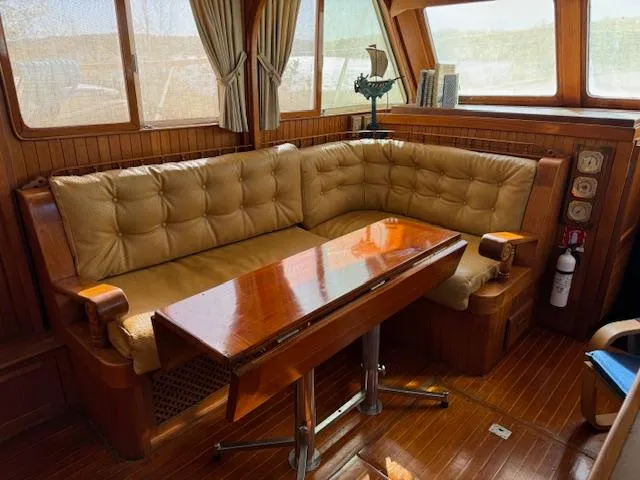 Slide: The Image of Interior of 1983 DeFever 41 Trawler with cushioned seating and wooden table. - 29