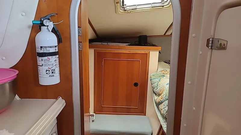 Slide: The Image of Interior of a 1999 PDQ 36 boat cabin with wood cabinetry and a fire extinguisher. - 10