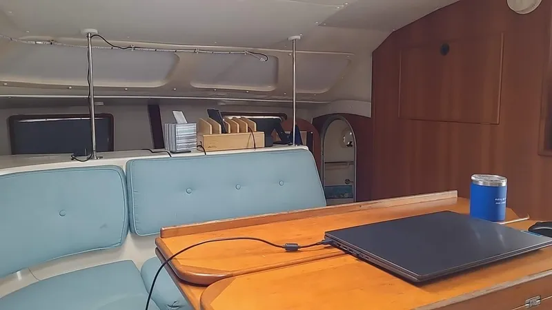 Slide: The Image of Interior of a 1999 PDQ 36 sailboat with blue seating and a wooden table. - 9