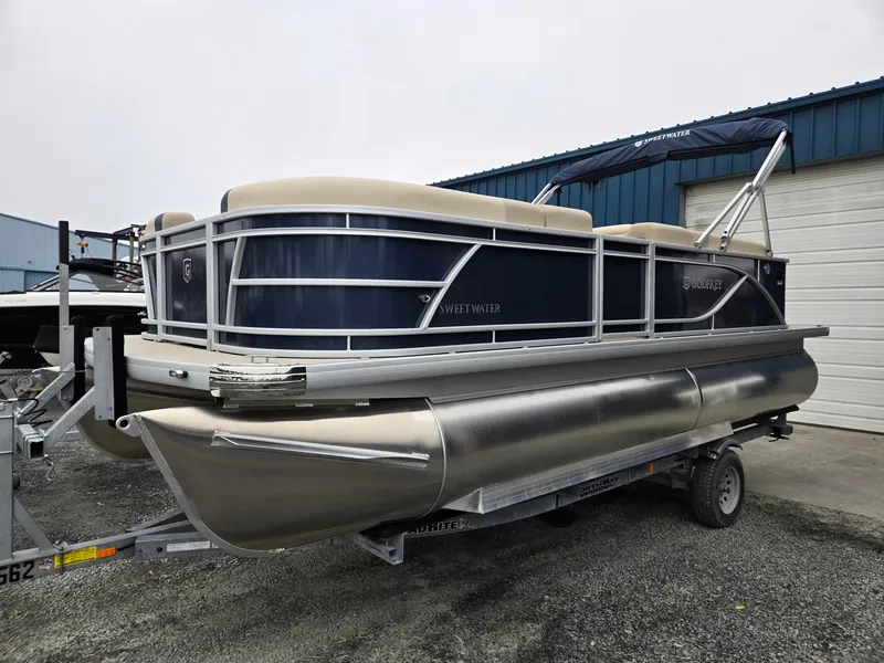 The Image of 2025 Godfrey Sweetwater 2086 C pontoon boat on trailer, parked outside a warehouse. - 0