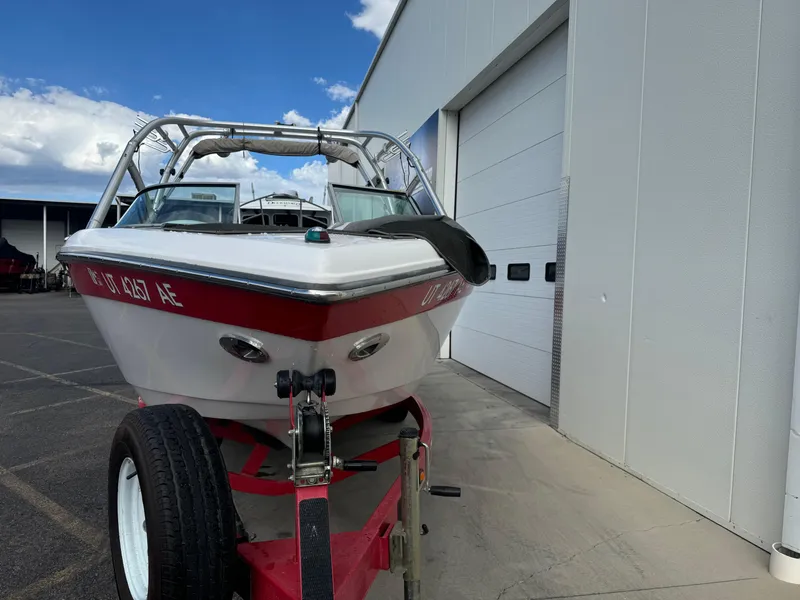 Slide: The Image of 2006 Moomba XLV boat on trailer near a white building under a blue sky. - 2