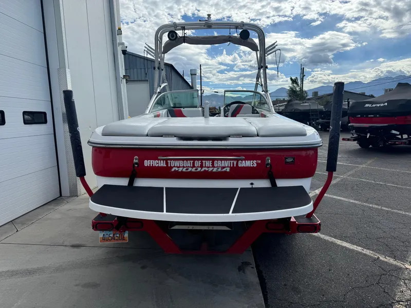 Slide: The Image of 2006 Moomba XLV boat, red and white, parked outdoors near a building. - 4