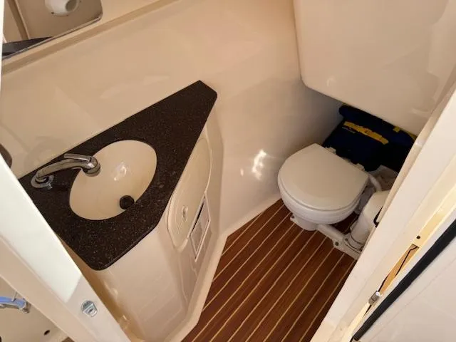 Slide: The Image of 2018 Scout 275 Dorado boat bathroom with sink and toilet, featuring wood-style flooring. - 12