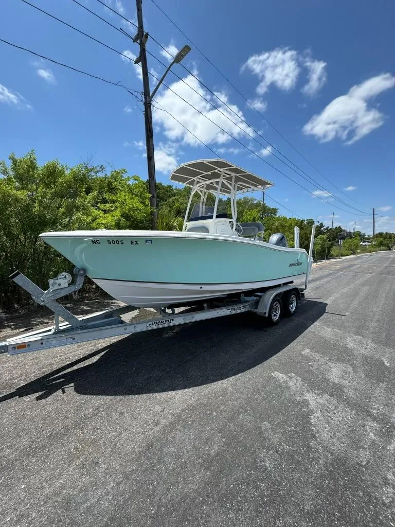 Slide: The Image of 2022 NauticStar 2102 Legacy boat on trailer, parked on sunny road. - 13