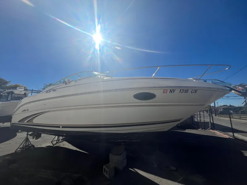 Slide: The Image of 2001 Sea Ray 245 Weekender boat under bright sun, parked on stands. - 2