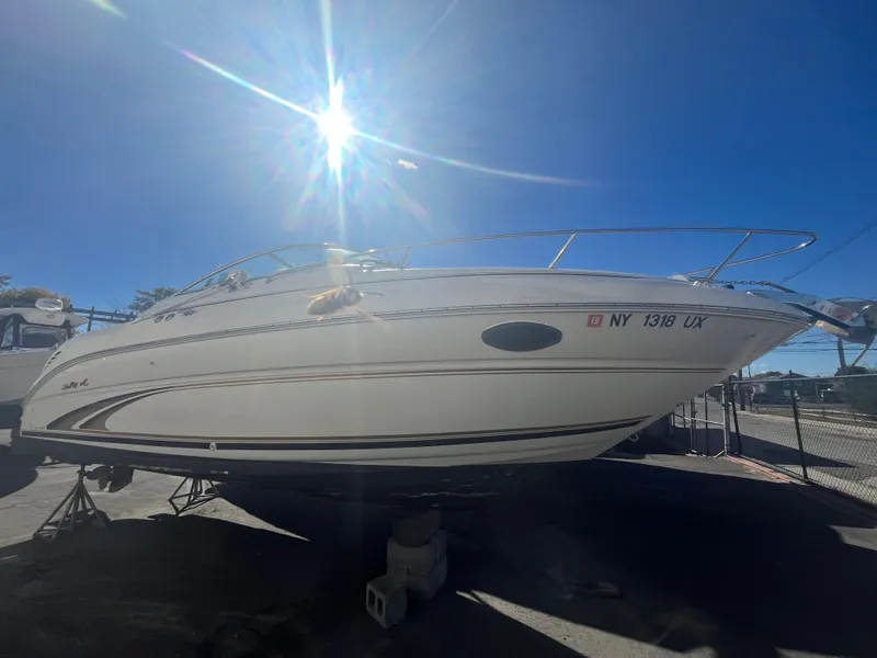 Slide: The Image of 2001 Sea Ray 245 Weekender boat under bright sun, parked on stands. - 3