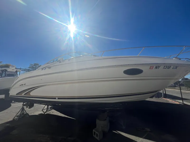 Slide: The Image of 2001 Sea Ray 245 Weekender boat under bright sun, parked on a trailer. - 4