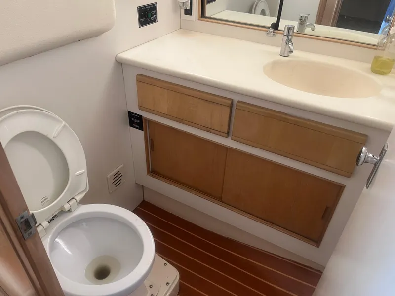 Slide: The Image of Bathroom interior of 1993 Bertram 37 Convertible yacht with wooden cabinets and toilet. - 37