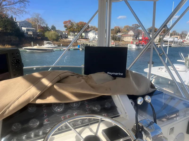 Slide: The Image of Bertram 37 Convertible 1993 boat helm with Raymarine equipment, docked in a scenic marina. - 4