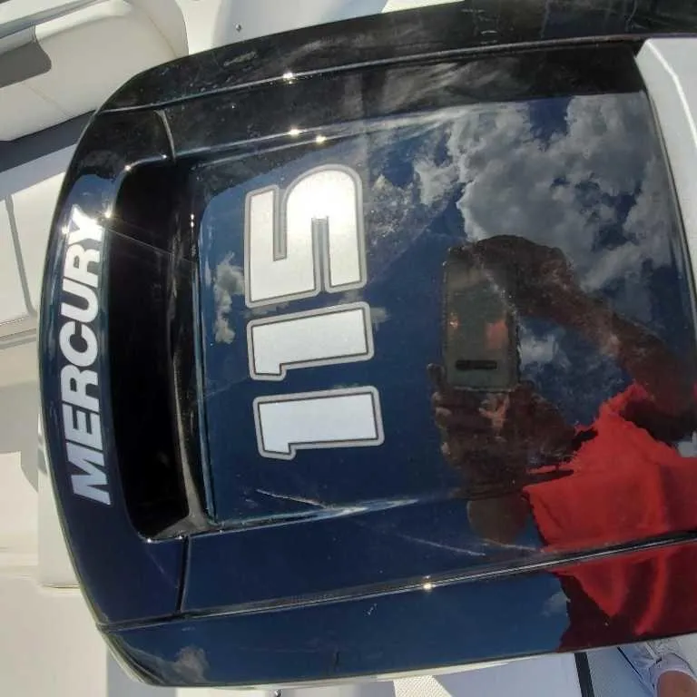 Slide: The Image of Mercury 115 outboard engine on 2025 Bayliner E18 boat, reflecting sky and person. - 11