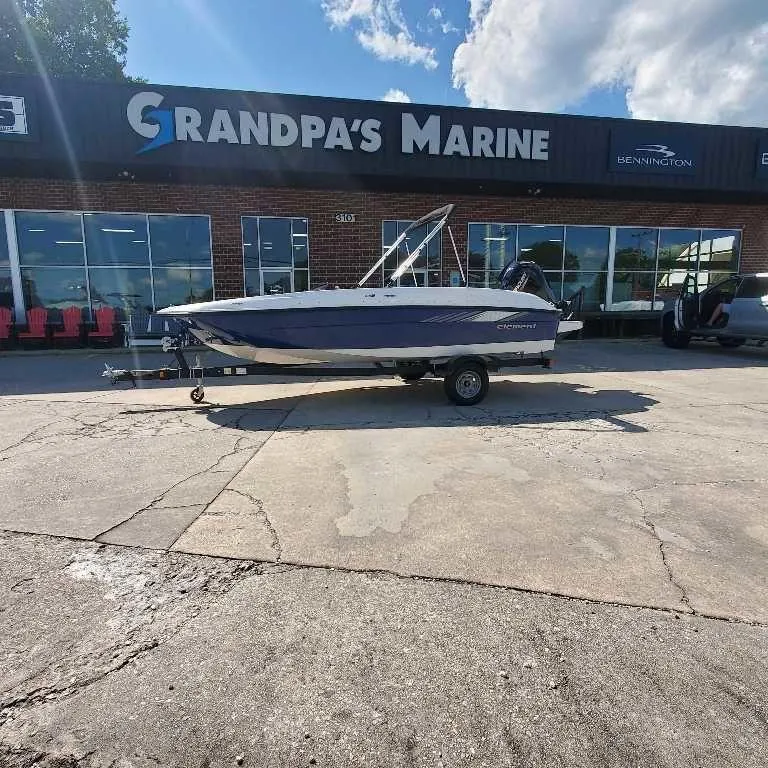 Slide: The Image of 2025 Bayliner E18 boat at Grandpa's Marine dealership under a sunny sky. - 2