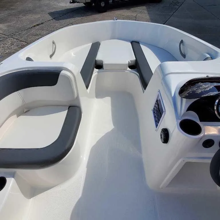 Slide: The Image of 2025 Bayliner E18 boat interior with seating and console, docked outdoors. - 4