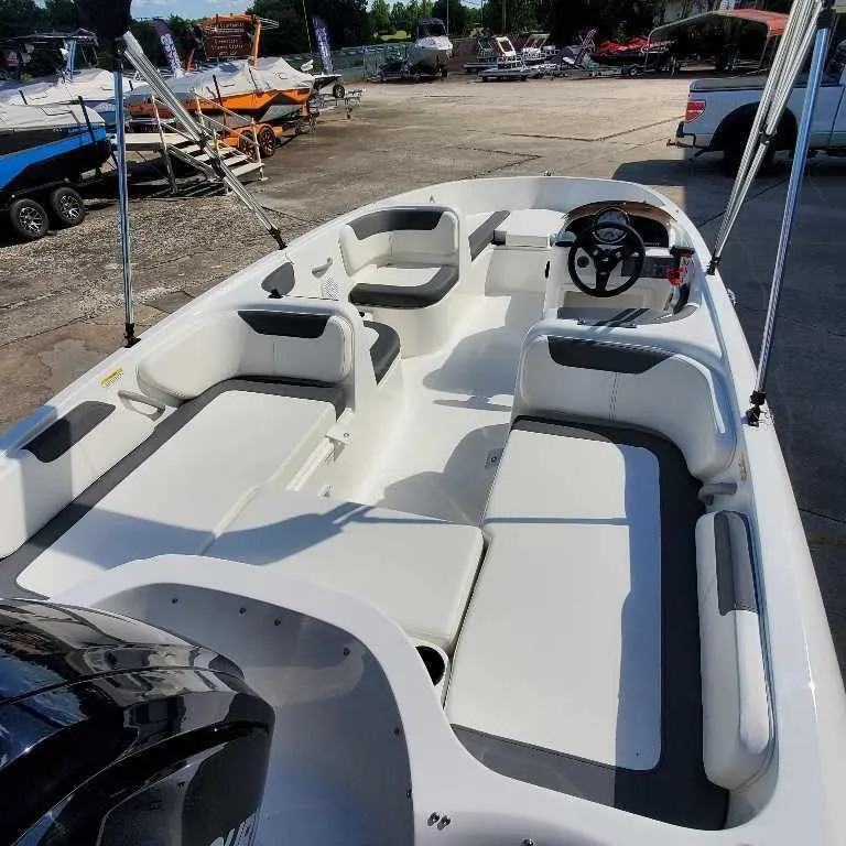 Slide: The Image of 2025 Bayliner E18 boat interior with seating and steering wheel, parked outdoors. - 5