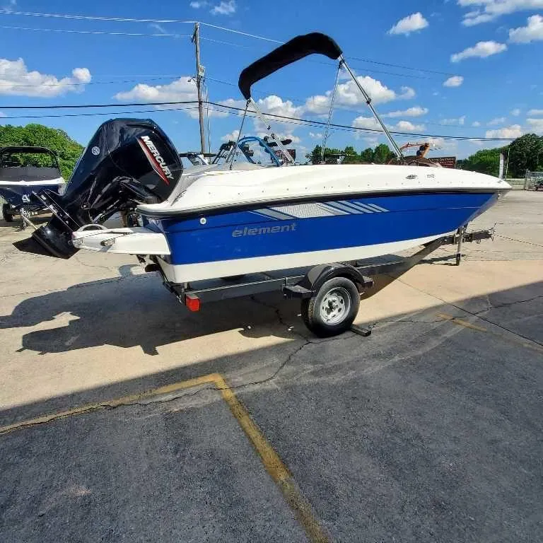 Slide: The Image of 2025 Bayliner E18 boat on trailer, blue and white design, sunny day. - 9