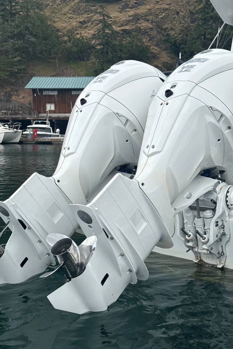 Slide: The Image of Twin outboard motors on a 2025 Sargo 31OB boat, docked near a wooded shoreline. - 19