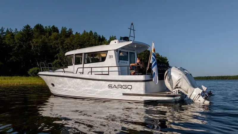 Slide: The Image of 2025 Sargo 31OB boat on calm water near forested shoreline. - 26