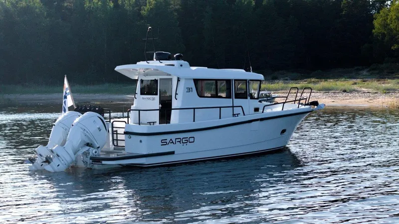 Slide: The Image of 2025 Sargo 31OB boat on calm water near a forested shoreline. - 28