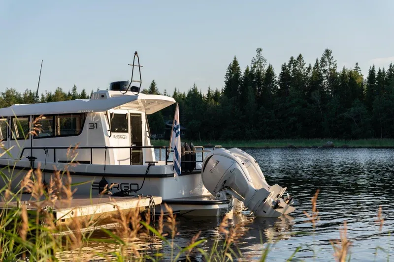 Slide: The Image of 2025 Sargo 31OB boat docked on a serene lake with forest backdrop. - 29