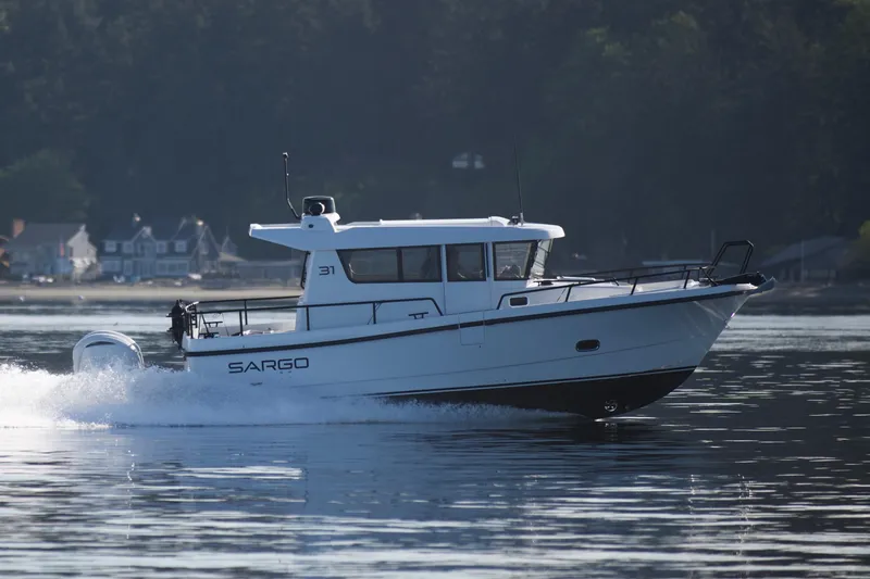 Slide: The Image of 2025 Sargo 31OB boat cruising on calm water near a forested shoreline. - 6