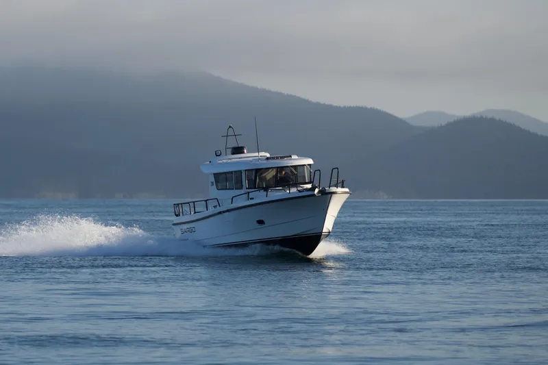 Slide: The Image of 2025 Sargo 31OB boat cruising on calm water with mountainous background. - 7
