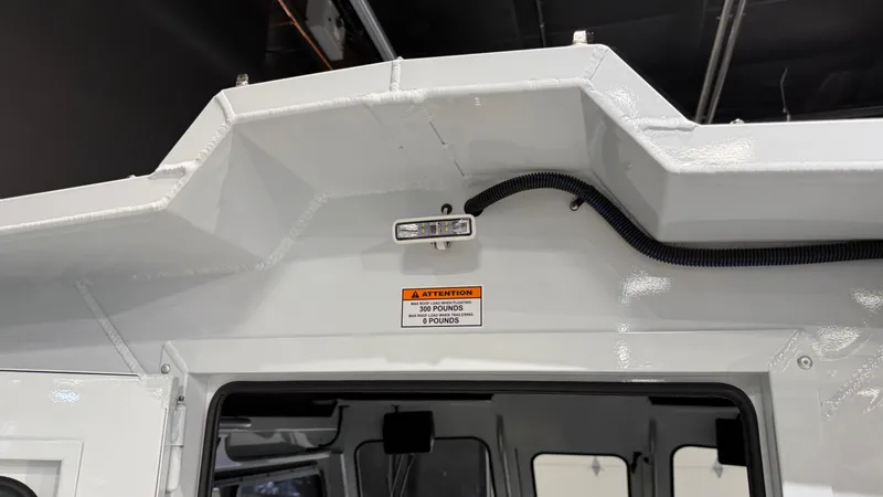 Slide: The Image of 2025 Hewescraft 240 Ocean Pro ET HT boat interior, featuring a warning label and wiring detail. - 36