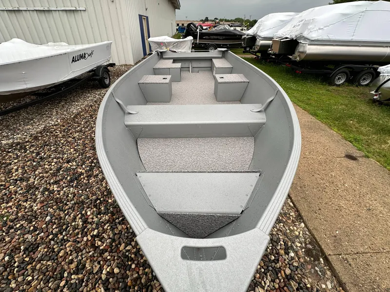 Slide: The Image of 2025 Alumacraft V14 boat on gravel, showcasing interior seating and storage. - 2