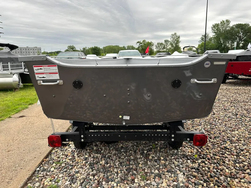 Slide: The Image of 2025 Alumacraft V14 boat on trailer, parked on gravel with overcast sky. - 6