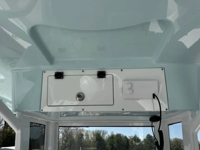 Slide: The Image of 2025 Sea Pro 262 DLX boat interior, featuring a storage compartment and electronic panel. - 12