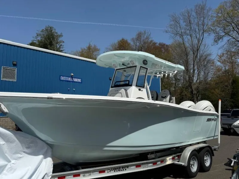 Slide: The Image of 2025 Sea Pro 262 DLX boat on trailer, parked near blue building. - 4