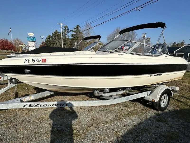 Slide: The Image of 2015 Stingray 191RX boat on trailer, parked outdoors under clear sky. - 14